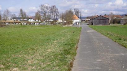 Bild: bkr
Auf der grünen Wiese, links von der Straße, ist einer der beiden Parkplätze für den Friedhof vorgesehen. Nach der neuen Planung für das Gewerbegebiet Schirnitzbach erhält er eine Trafostation für Elektrofahrzeuge.
