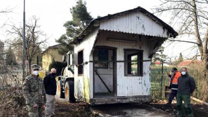 Bild: mor
Das alte Wachhäuschen vom Gate 1 auf dem „Rückflug“ ins Lager. Command Sergeant Major Mark Morgan (von links) dankt Chris Irwin, den Arbeitern der Bauabteilung und Hausmeister Thomas Bernhard für die Sicherung des Relikts aus alten Zeiten.