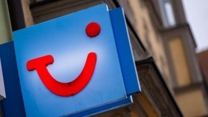 Symbolbild: Nicolas Armer/dpa
Das Logo des Reiseunternehmens TUI ist an der Fassade eines Reisebüros.
