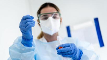 Symbolbild: Jean-Christophe Bott/KEYSTONE/dpa
Eine Krankenschwester steckt eine Probe mit einem Nasenabstrich eines Patienten, der auf das Coronavirus getestet wird, in einen Behälter.