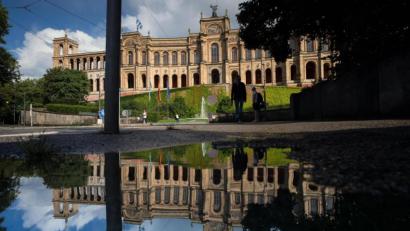 Archivbild: Peter Kneffel/dpa
Das Maximilianeum, das den bayerischen Landtag beherbergt, spiegelt sich in einer Pfütze auf der nassen Straße.