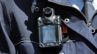 Symbolbild: Federico Gambarini
Eine Polizistin trägt eine „Bodycam“ an ihrer Uniform. Foto: Federico Gambarini/Archiv