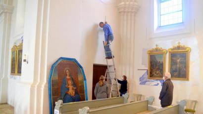 Bild: fjo
Pfarrer Georg Hartl (rechts) lässt sich die Rückkehr und Montage des aufwendig restaurierten Mariengemäldes (links) durch die Mitarbeiter der Fachwerkstatt Rappenegger auf seinen alten Platz in der Emmeramskirche nicht entgehen.