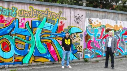 Bild: njn
Eine Seite der Bretterwand am Skaterplatz hat der Graffity-Künstler Fabian Moller (links) schon gestaltet. Bürgermeister Johannes Reger (rechts) freut sich auf mehr.