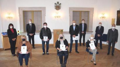 Bild: LRA Neustadt/ Marcel Weidner/exb
Landrat Andreas Meier (stehend, Zweiter von links) verabschiedet langjährige Mitarbeiter in der Kreisverwaltung.