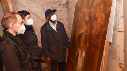 Bild: tsp
Die beiden Kunsthistoriker Dr. Daniel Rimsl und Anne Wiegand (von links) begutachten auf dem Dachboden der Sakristei gemeinsam mit Pfarrer Dr. Charles Ifemeje das Bild des heiligen Martin. Maurus Fuchs, damals knapp 30 Jahre alt, hat es um 1801 für die Pfarrkirche St. Martin in Griesbach gemalt.