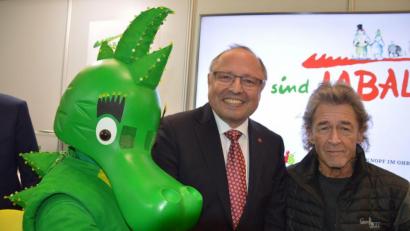 Bild: we
Ernst Kick (Mitte) und Peter Maffay mit Tabaluga bei der Spielwarenmesse im Jahr 2018.