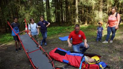 Bild: bkr
Für Dennis, Michael und Tom (von links) und Hanna im Rettungssack war es die letzte Gruppenstunde bei den Feuerdrachen. Roland Kreuzer leitete die Station der Bergwacht. Mit auf dem Bild Angelika Scherm mit Sohn Luis. Beide führten die Gruppe sicher zu den acht Stationen im Wald.