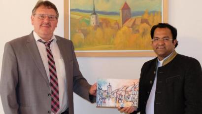 Bild: Stefanie Gradl
Im Rathaus gratuliert Bürgermeister Hans-Martin Schertl (links) Pater Robin zum zehnjährigen Dienstjubiläum und überreicht ihm eine Leinwand mit dem Vilsecker Marktplatz.