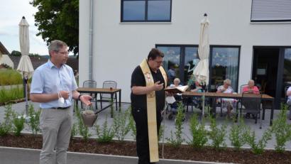 Bild: gi
Pfarrer Udo Klösel segnete das neue Haus der „Wohnanlage und Tagespflege an der Wieskirche" in Moosbach“. Der frühere Bürgermeister und jetzige Gemeinderat Hermann Ach assistiert dazu als Ministrant. Ach gilt als Initiator des Gebäudebaues in den Jahren 2019/2020.