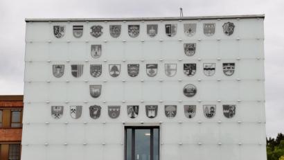 Bild: td
Die Glasfassade am Neubau des Landratsamts zeigt neben dem Wappen des Landkreises die Wappen der kreiszugehörigen Gemeinden. Eines sticht heraus, es ist rund und eigentlich kein Wappen (zweite Reihe von unten).