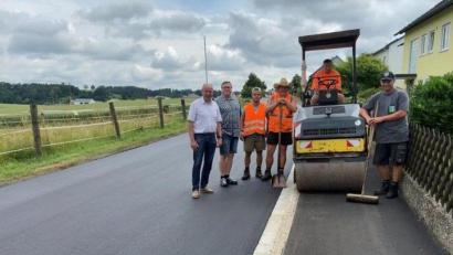 Bild:  Hans Oberndorfer/exb 
Ein Bild von der sanierten Siedlerstraße machen sich vor Ort Bürgermeister Roland Strehl, der gemeindliche Bautechniker Michael Pollok (von links) und Mitarbeiter der ausführenden Firma Englhard.