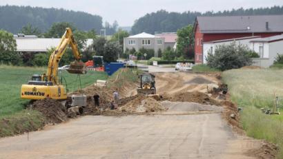 Bild: frd
Die alte Asphaltdecke ist bereits verschwunden: Die Arbeiten für den Ausbau der Gemeindestraße vom Oberviechtacher Industriegebiet West (im Hintergrund) bis zum Ortsteil Hof laufen seit Ende Mai.