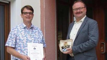 Bild: bk
Bürgermeister Uwe König (rechts) gratuliert Amtsrat Max Heindl zum Dienstjubiläum mit Urkunde und Gemeindewappen.