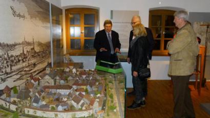 Bild: lg
Wilfried Neuber (links) erklärt bei einer Museumsführung anhand eines Modells und des Merianstichs den Aufbau des Marktes Oberviechtach und seiner Befestigung mit Mauer, Türmen und Graben. Wie es beim Museumsverein weitergeht, steht nach einer erfolglosen Neuwahl in den Sternen.
