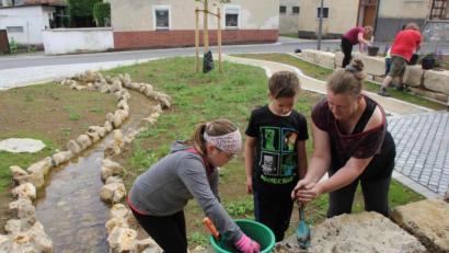 Bild: ads
Daniela Dotzler (rechts), die die Kinder- und Jugendgruppe des OGV Großschönbrunn leitet, zeigte dem Nachwuchs, wie die Ritzen zwischen den großen Steinquadern mit Erde gefüllt worden, damit dort Hauswurz gepflanzt werden kann.
