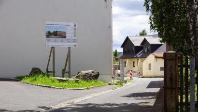 Bild: bkr
Wo die Bautafel steht, sollen die Fahrradständer für die Besucher des Bürgerhauses platziert werden. Im Eingangsbereich lehnt die Regierung diese ab. Gleichzeitig wird die weiße Asphaltdecke nach vorne verlegt.