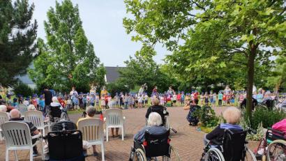 Bild: e
Im Garten des AWO-Heimes unterhalten die Mädchen und Buben der Kindertagesstätte Arche Noah die Senioren mit Liedern.