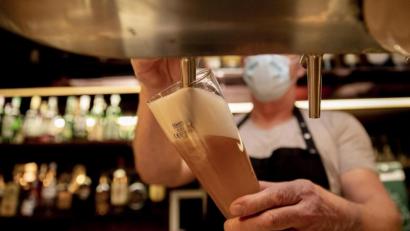 Symbolbild: Christoph Soeder/dpa
Ein Wirt mit Maske zapft in einer Kneipe ein Bier.