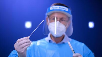 Symbolbild: picture alliance/Robert Michael/dpa-Zentralbild/dpa
Ein Arzt hält in einer Corona-Teststation für Urlaubsrückkehrer einen Coronavirus-Test in den Händen.