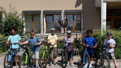 Bild: Katja Stiegler/exb
Fahrrad und Handy parat: Die Actionbound-Tester starten das Hahnbacher Abenteuer bei der Jubiläumsfahne vor dem Rathaus.