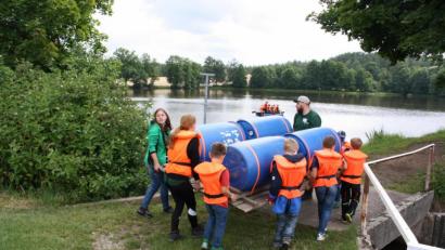 Bild: bjp
Gemeinsam bugsieren Erzieher und Kinder das Floß vom Dorfplatz zum gleich nebenan gelegenen Heindlweiher: Spielerisches Sozialkompetenztraining im Team steht bei den "Lerning Campus"-Ferienfreizeiten als Lernziel an oberster Stelle.