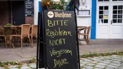Bild: Daniel Bockwoldt/dpa
Eine Tafel mit der Aufschrift "Bitte Registrieren nicht vergessen. Danke" steht vor einem Restaurant.