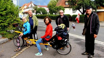 Bild: ds
Malte Boßert und Tilmann Jiménez Reichow machen mit ihrem Liegetandem halt in Neukirchen (von links). Zur Begrüßung stehen (von links) Zweiter Bürgermeister Christian Sperber, Erich Neumüller und Kreisheimatpfleger Walter Schraml bereit.