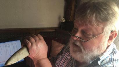 Bild: ihl
Heinrich Schwarz demonstriert wie Ururahnen mit dem Steinbeil gearbeitet haben. Wegen des Lochs geht er davon aus, dass für das Werkzeug noch eine andere Verwendung gab. Meist wurden diese Geräte zum Baum fällen und auch zum Spalten benutzt.