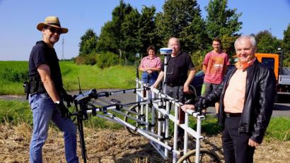 Bild: bkr
Mit einem Magnetometer suchte Dr. Markus Tarasconi (links) nach Spuren der Vergangenheit in der Erde. Bürgermeister Günter Kopp (rechts) und Hans Bäte (Mitte) ließen sich das Verfahren erklären. Auch die Grundstückseigentümer im Hintergrund sind gespannt auf das, was möglicherweise in ihrem Boden verborgen ist.
