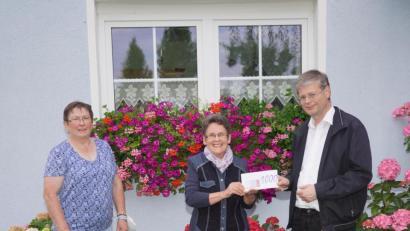 Bild: fvo
Der Waldthurner Pfarrer Norbert Götz und dessen „Pfarrköchin“ Elisabeth Kodalle (links) freuen sich im Garten von Christa Wildenauer über 1000 Euro für die Renovierung der Rosenkranzstationen zum Fahrenberg.