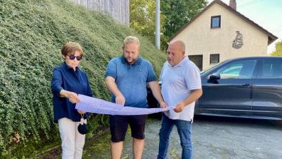Bild: Eichl
Marianne Rauh lässt sich den Bauzeitenplan von Daniel und Wolfgang Scharnagl erläutern (von links); die Baufirma versichert, Ende November 2022 sei die Dorferneuerung abgeschlossen.