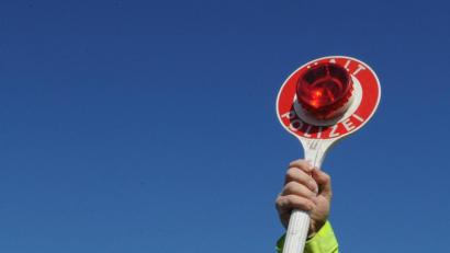 Symbolbild: Patrick Seeger/dpa
Polizeikelle in der Hand eines Polizisten bei einer Kontrolle.