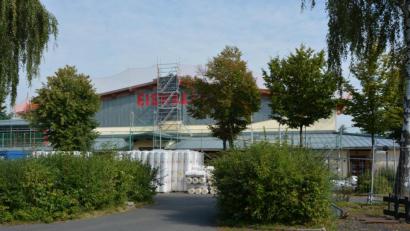 Bild: jr
Eingerüstet ist seit kurzem die Eishalle, wo die ersten Sanierungsarbeiten begonnen haben. Vor dem Gebäude türmen sich Baumaterialien.