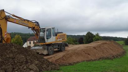 Bild: Houschka
Sieht aus wie ein Übungsgelände für Mountainbiker, ist aber die Folge einer unliebsamen Überraschung: Gleich neben dem Rathaus in Wolfring (im Hintergrund) türmen sich riesige Sandberge, die über Jahrzehnte hinweg im Unterbau einer Gemeindeverbindungsstraße lagen