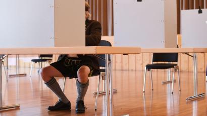 Bild: Angelika Warmuth/dpa
Ein Mann in Tracht sitzt im Wahllokal.