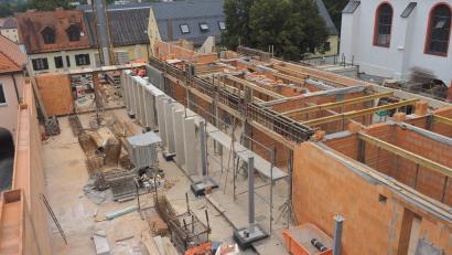 Bild: ws
Vom Gerüst am Hauptgebäude des neuen Rathauses bietet sich ein Überblick über die neuen Bereiche. Rechts die Räume für öffentliche Toilette und die Verwaltung, ober wird noch ein zweites Stockwerk aufgesetzt. Hinten wird einmal der Rathaussaal entstehen. Die linke Seite des Areals nimmt der Innenhof ein. Ihn trennt einmal eine Mauer vom Nachbargrundstück.