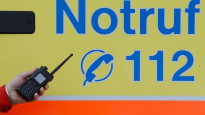 Symbolbild: Jens Kalaene/dpa
Ein Sanitäter vor einem Rettungswagen mit der Nummer des Notrufes.