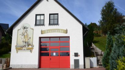 Bild: bey
Das Feuerwehrhaus Neudorf erhält rechts einen Queranbau. Die jetzige Außentreppe wird dann zur Innentreppe. In der bestehenden Garage (rotes Tor) werden Umkleide- und Sanitärräume eingebaut.