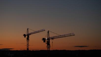 Symbolbild: Robert Michael/dpa
Kräne stehen vor dem Abendhimmel auf einer Baustelle.