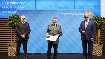 Bild:  Bayerisches Staatsministerium des Innern, für Sport und Integration/exb
Stellvertretender Landesschützenmeister Dieter Vierlbeck (links) und Bayerns Innen- und Sportminister Joachim Herrmann (rechts) gratulieren Albert Riedl.