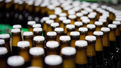 Archivbild: Rainer Jensen/dpa
Bierflaschen mit Kronkorken laufen durch die Produktion. Foto: Rainer Jensen/dpa/Archivbild
