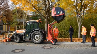 Bild: bey
Das Laub wird mit dem vorn am Traktor montierten Sauggerät von den Gehwegen entfernt und im Container am Heck des Traktors gesammelt. Zum Entleeren kann der Container nach oben gehoben und dann beispielsweise auf die Ladefläche eines LKW entleert werden. Bauhofmitarbeiter Harald Kres (links) und Bauhofleiter Stephan Gloßner (rechts) stellen Bürgermeister Sebastian Hartl und Geschäftsleiter Michael Gräf die am Traktor montierte neueste Errungenschaft des Bauhofs vor.