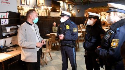 Bild: Felix Hörhager/dpa
Polizeibeamte sprechen bei einem Pressetermin zu Corona-Kontrollen in München in einem Restaurant mit dem Restaurantleiter Bardis Jason, um vor den Augen der Medien die Einhaltung der Corona-Regeln zu überprüfen.