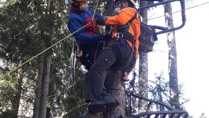Bild: exb/Bergwacht Amberg
Auf dem Bild ist zu sehen, wie ein Bergretter, ausgerüstet mit Baumrettungsmaterial, den Übungspatienten im Kletterhochsitz für das Abseilen aus acht Metern Höhe vorbereitet.