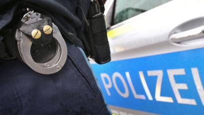 Bild: Karl-Josef Hildenbrand
Ein Polizist mit Handschellen und einer Pistole am Gürtel steht vor einem Streifenwagen. Foto: Karl-Josef Hildenbrand/dpa