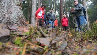 Bild: gri
Markus Raum (rechts) und seine Wanderguppe auf einem Hügelgrab bei Aschach. Im Vordergrund liegen Steine, die wohl einst beim Aufschütten verwendet wurden.