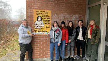 Bild: Otto-Hahn-Gymnasium/exb
Die Theatergruppe des Otto-Hahn-Gymnasiums mit Künstler Nils Oskamp (links) vor dem fertigen Graffiti-Kunstwerk.