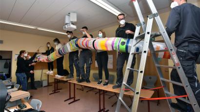 Bild: Stephan Huber
Die beteiligten Schülerinnen der Dr.-Johanna-Decker-Schulen und Azubis der Firma Baumann befestigen gemeinsam das Hauptrohr der Lüftungsanlage an der Klassenzimmerdecke.
