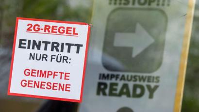 Bild: Peter Kneffel/dpa
Ein Schild mit der Aufschrift „2G Regel - Eintritt nur für: Geimpfte oder Genesene“ steht vor einer Bar.
